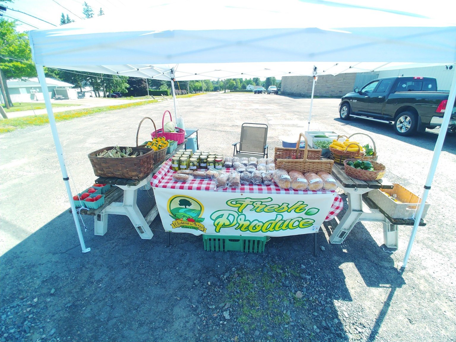 Fresh produce, baked goods, and preserves displayed under the farm-stand canopy