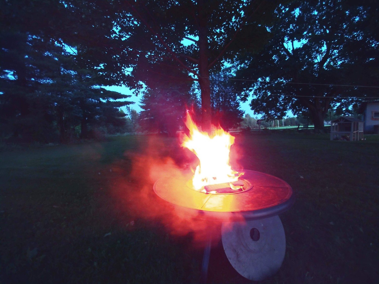 A backyard fire burning at dusk